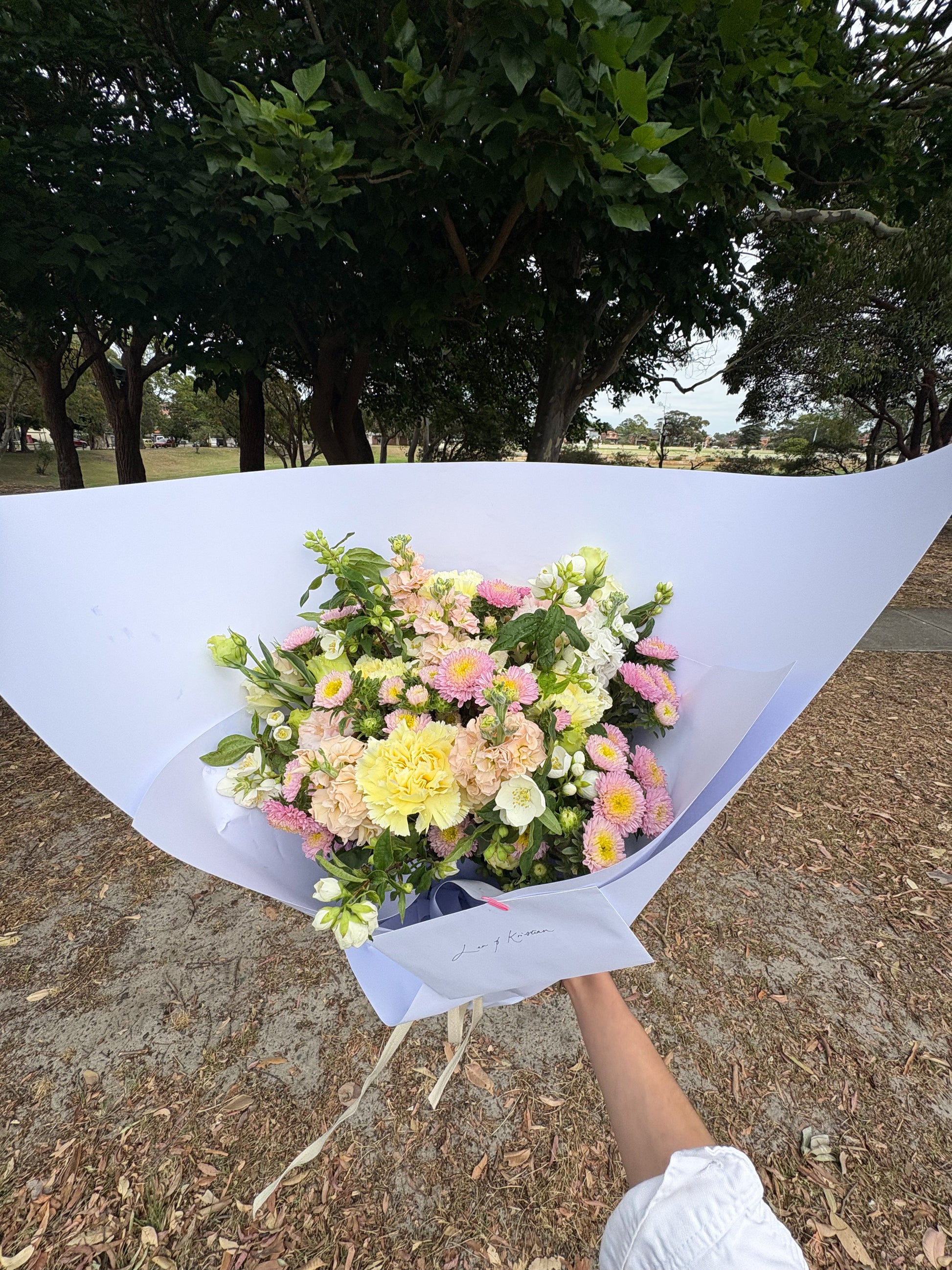 Bouquet of flowers held outdoors with trees in the background