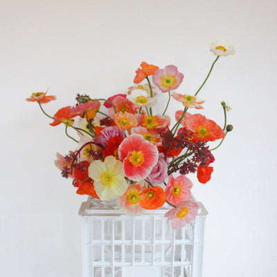 Custom seasonal arrangement featuring poppies and roses