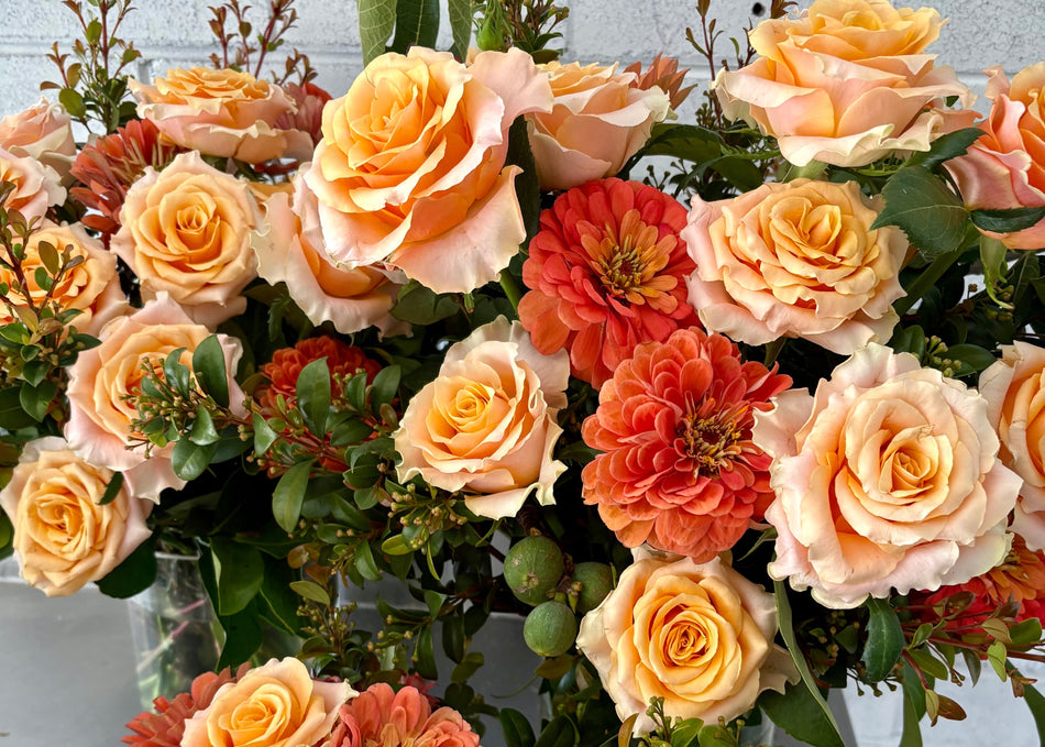 Vase arrangements of orange and green flowers, foliage and fruit
