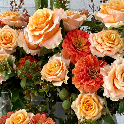 Vase arrangements of orange and green flowers, foliage and fruit