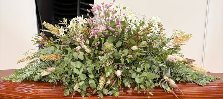Plastic free funeral spray atop a wooden coffin