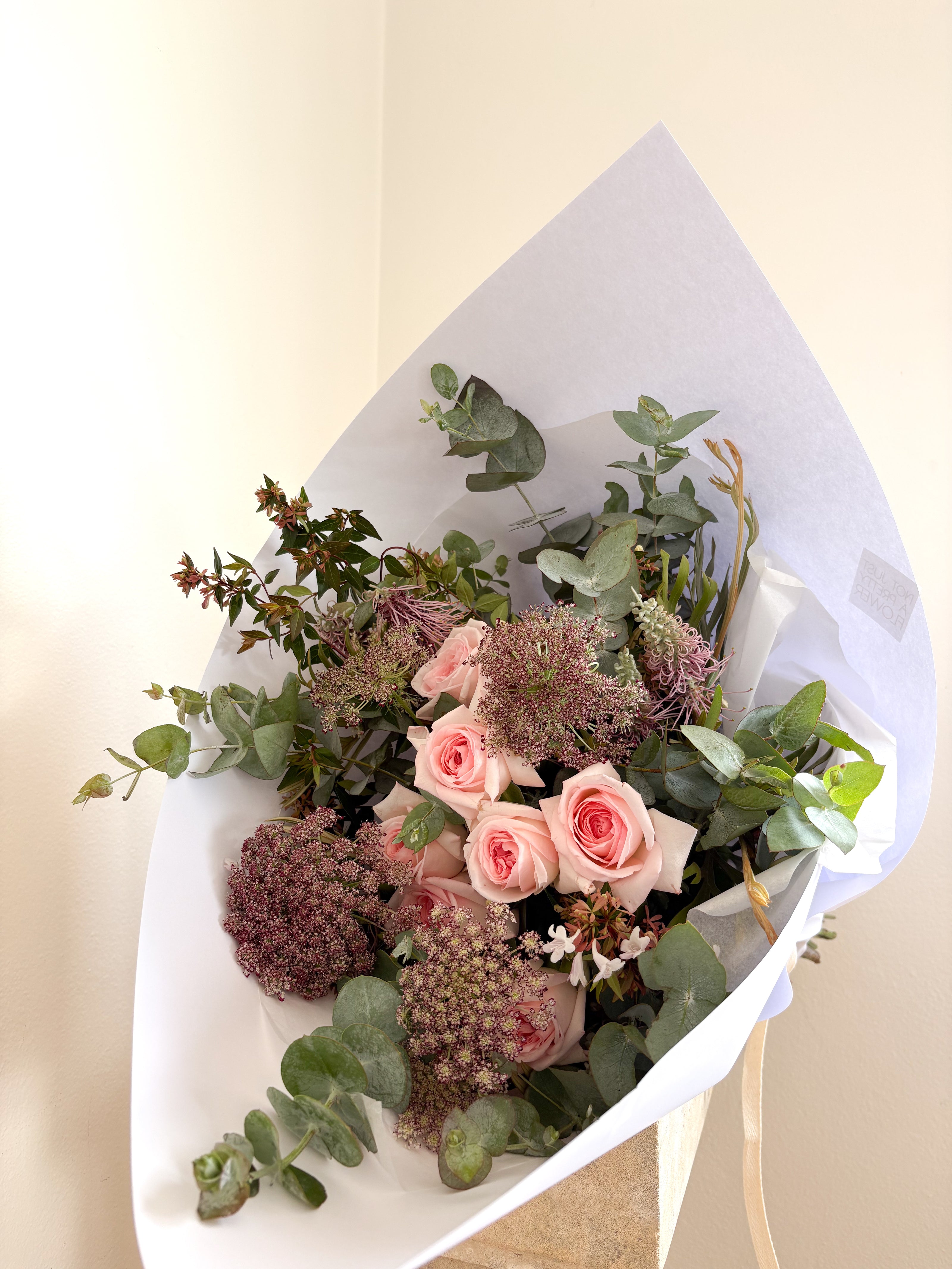 Bouquet of flowers wrapped in white paper on a light background