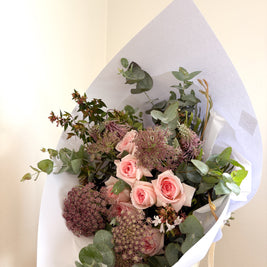 Bouquet of flowers wrapped in white paper on a light background