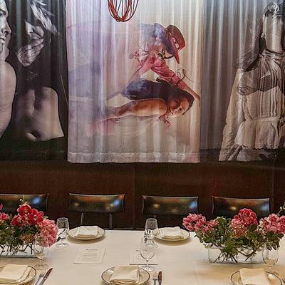 Dining table set with floral centerpieces, plates, and cutlery against a backdrop of artistic murals and lighting by Moya Delany at Eleven Barrack private event space